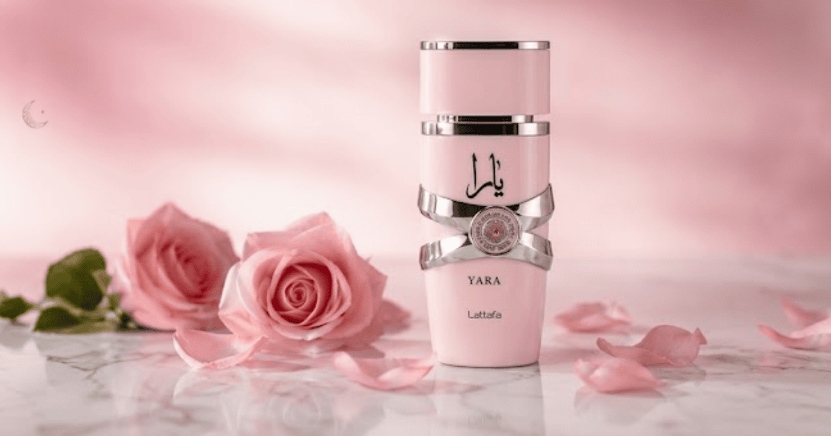 Frasco rosa do perfume Yara Lattafa sobre superfície de mármore branco com rosas cor-de-rosa, pétalas e flores brancas ao redor, perfume Yara notas florais árabes feminino.